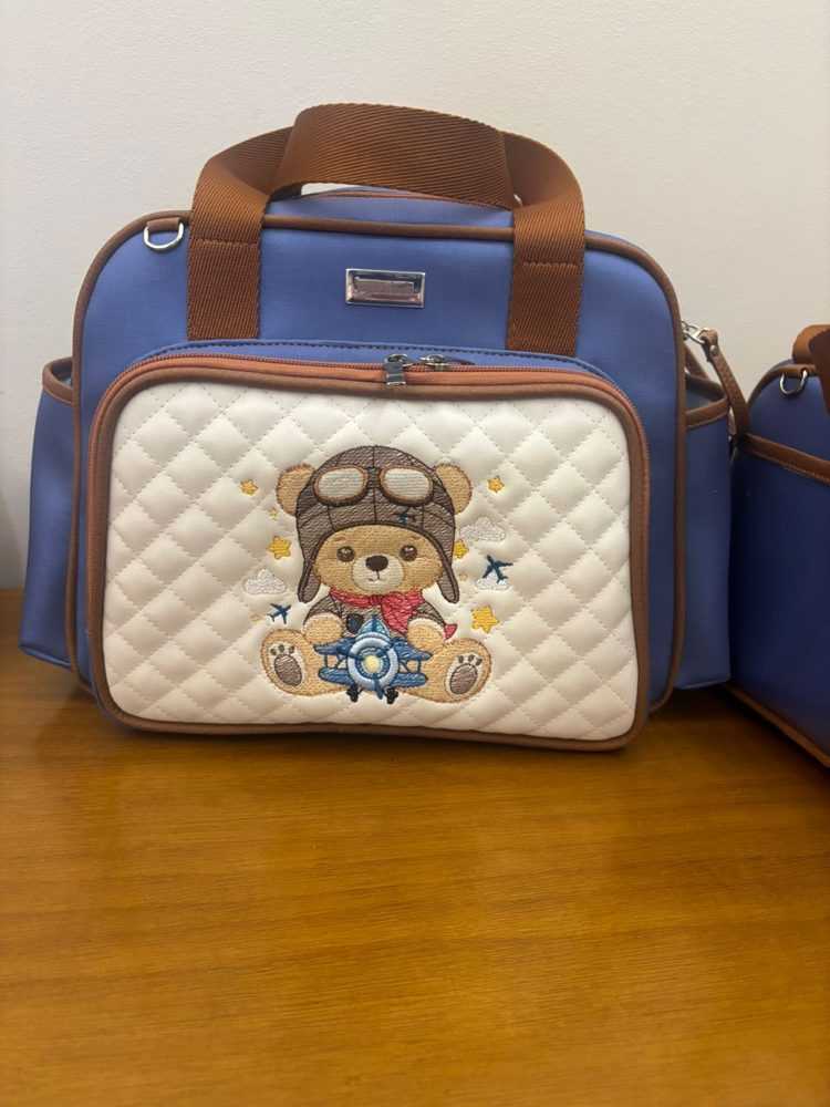Bolsa maternidade azul com frente matelassê e bordado de ursinho aviador